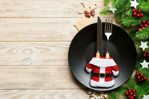 vue de dessus du dîner de noël sur fond en bois. assiette, ustensile, sapin et décorations de vacances avec espace de copie. concept de temps du nouvel an photo