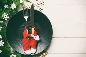 vue de dessus du dîner de noël sur fond en bois. assiette, ustensile, sapin et décorations de vacances avec espace de copie. concept de temps du nouvel an photo