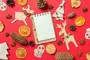 vue de dessus du cahier, fond rouge décoré de jouets festifs et de symboles de noël rennes et arbres du nouvel an. notion de vacances photo