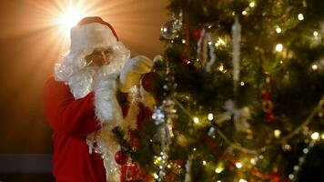 Père Noël claus décore le Noël arbre. fermer de Père Noël claus décorer le Noël arbre. Père Noël claus décore le Noël arbre sur une de fête nuit. photo