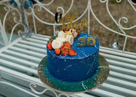 30 ans anniversaire bleu gâteau avec des fraises sur d'or assiette photo