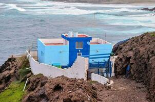 une bleu maison sur le falaise surplombant le océan photo