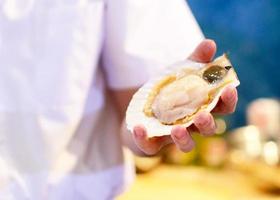 coquille de pétoncle fraîche à portée de main chef, pétoncle cru propre et ouvert photo