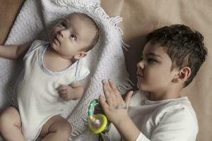 deux frères mensonge et posant. portrait de frères. deux mois bébé garçon et cinq ans petit garçon en jouant gaiement. vue de au-dessus de. émotif expressions de les enfants. photo