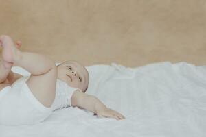 6-8 mois bébé garçon mensonge ludique dans lit. charmant 6-7 mois peu bébé dans blanc le maillot de corps. bébé garçon dans blanc literie. copie espace photo