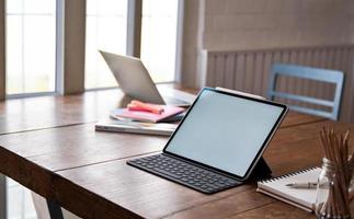 écran vierge de la tablette et équipement de bureau sur table en bois. photo