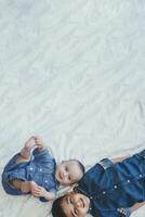 content enfance concept. content frères portrait. 6 ans garçon et 6 mois vieux bébé garçon ayant amusement. deux peu des gamins souriant à le caméra. mignonne peu frères mensonge sur lit ensemble photo