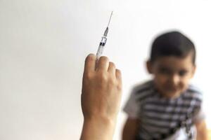 une médecin vacciner Jeune patient. peu garçon effrayé de injection. enfant immunisation, enfants vaccination, santé concept. photo