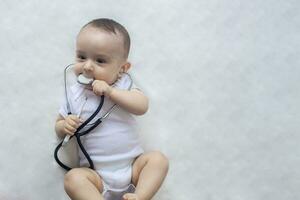 peu mignonne bébé médecin. 6 mois vieux bébé garçon en jouant avec stéthoscope. enfant ayant amusement comme une médecin photo