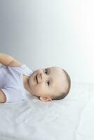 6 mois bébé ayant amusement dans blanc literie. mignonne bébé mensonge sur lit. famille, Nouveau vie, enfance concept. photo