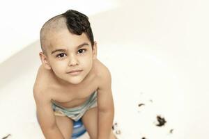 six ans garçon à Coupe de cheveux à maison. père Couper moitié de le fils cheveux de à le salle de bains photo