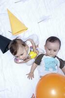 deux bébés en jouant avec des ballons et anniversaire casquettes. frère et sœur en jouant ensemble photo