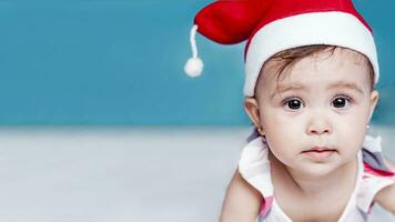 peu Père Noël. 1 an bébé fille dans Père Noël claus chapeau. joyeux Noël. adorable moyen-orient fille dans Père Noël casquette. photo