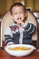 pleurs bébé garçon. en colère peu enfant dans le cuisine photo