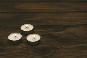 Trois paraffine flottant bougies sur une en bois tableau. photo