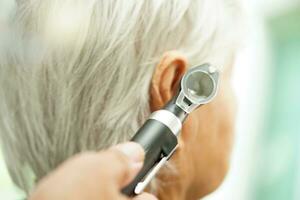 oto-rhino-laryngologiste ou ent médecin médecin examiner Sénior patient oreille avec otoscope, audition perte problème. photo