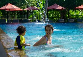 asiatique enfant garçon apprendre nager dans une nager bassin avec maman photo