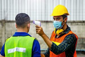 ouvrier vérifier corps Température avant travail dans le entrepôt photo