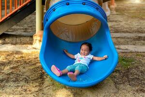 asiatique fille est prendre plaisir sur une terrain de jeux équipement dans une école. photo