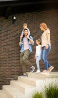 famille avec une mère, père, fils et fille en marchant par le mur de brique maison photo