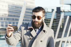 Jeune hipsters homme d'affaire prendre selfie dans une moderne ville photo