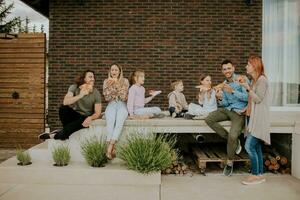 groupe de Jeune gens et des gamins en mangeant Pizza dans le maison arrière-cour photo