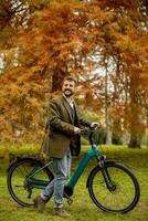 beau jeune homme avec vélo électrique dans le parc en automne photo