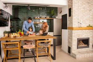 Jeune famille en train de préparer des légumes dans le cuisine photo