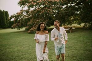 une content Jeune couple est profiter le magnifique alentours de une jardin avec des lunettes de Frais limonade photo