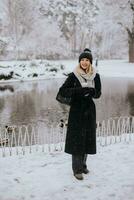 Jeune femme dans chaud vêtements profiter dans neige avec à emporter café tasse photo