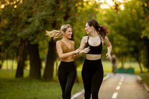 deux jolie Jeune femmes fonctionnement sur le voie dans le parc photo