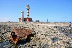 une rouillé bateau est séance sur le rochers près une phare photo