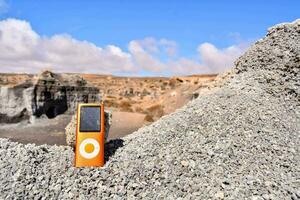 un Orange la musique joueur séance sur Haut de une pile de rochers photo