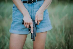 une fille dans denim short et avec une pistolet dans sa main pose pour une photo.. fermer photo