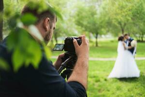 le vidéaste pousses le les mariés dans le jardin dans le été. photo