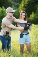 une fille apprend à tirer une pistolet avec un instructeur à le formation sol photo