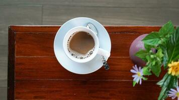 blanc tasse de noir café avec une soucoupe et une partie de vase sur une tableau. Haut vue sur une en bois tableau. photo