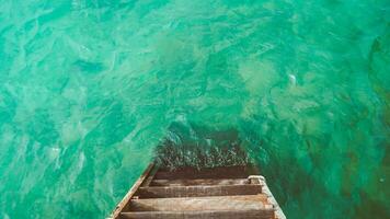 vide jetées. en bois escalier Aller dans le mer avec petit vagues et turquoise l'eau. photo