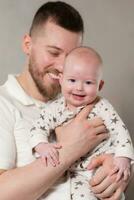 papa détient le sien fils dans le sien bras. père pièces avec nouveau née bébé à maison. photo