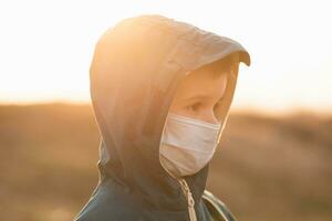 portrait de une Jeune enfant dans une médical masque sur le rue pendant le coronavirus et convoitise pandémie - 19 photo