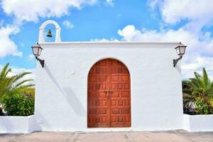 une blanc église avec une en bois porte et cloche photo