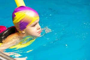 petit enfant nager dans un intérieur bassin. photo