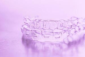 invisible dentaire les dents supports dent aligneurs sur rose Contexte. Plastique un appareil dentaire dentisterie retenues à redresser dents. photo