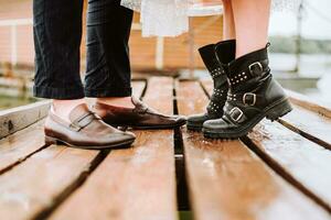 jambes de le jeunes mariés sur le Contexte de le jetée.la la mariée et jeune marié supporter et pose dans des chaussures sur le quai. photo