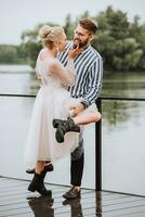 le magnifique jeunes mariés elles ou ils rire, avoir amusement et réjouir sur le jetée. photo