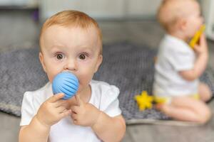 mignonne content des gamins jouer ensemble sur le sol avec jouets et prendre leur dans bouche photo