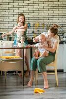 deux Jeune les mères ensemble alimentation leur content bébés Lait bouillie dans le cuisine photo