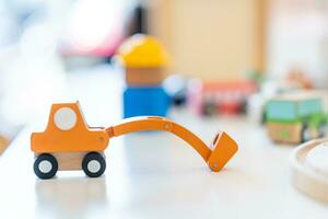 un Orange en bois jouet excavatrice est mis sur le table dans de face de autre floue en bois jouets. photo