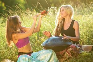 Jeune femmes jouer et chanter sur le musical instrument handpan. entraine toi méditation à le coucher du soleil photo