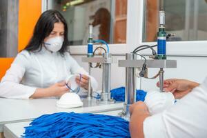 une femme travaux à une machine pour le fabrication de médical masques avec nanofibre et souder boucles à leur avec ultrason. coronovirus et covid-19 la prévention photo